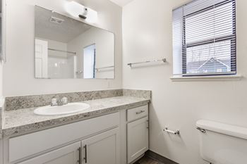A white bathroom with a sink, mirror, and tub.